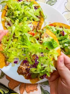 breaking loaded tostada in half to eat it