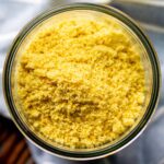 fluffy grated vegan parmesan substitute in glass mason jar with blue towel in background