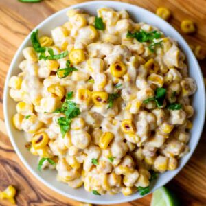 creamy spicy mexican-style street corn in a white bowl with cilantro sprinkled on top