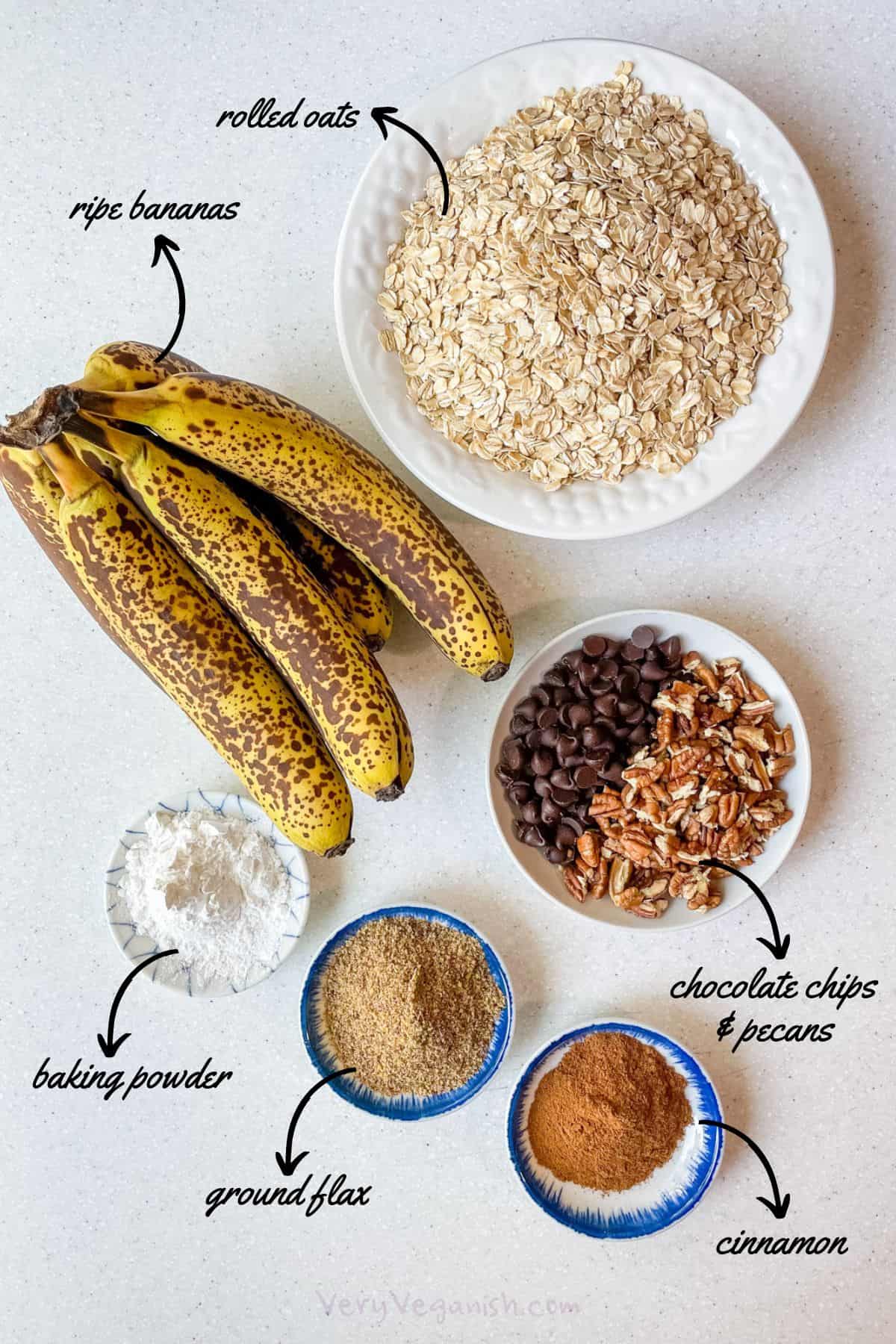 Ingredients on counter: ripe bananas, rolled oats, baking powder, ground flax, cinnamon, chocolate chips and pecans