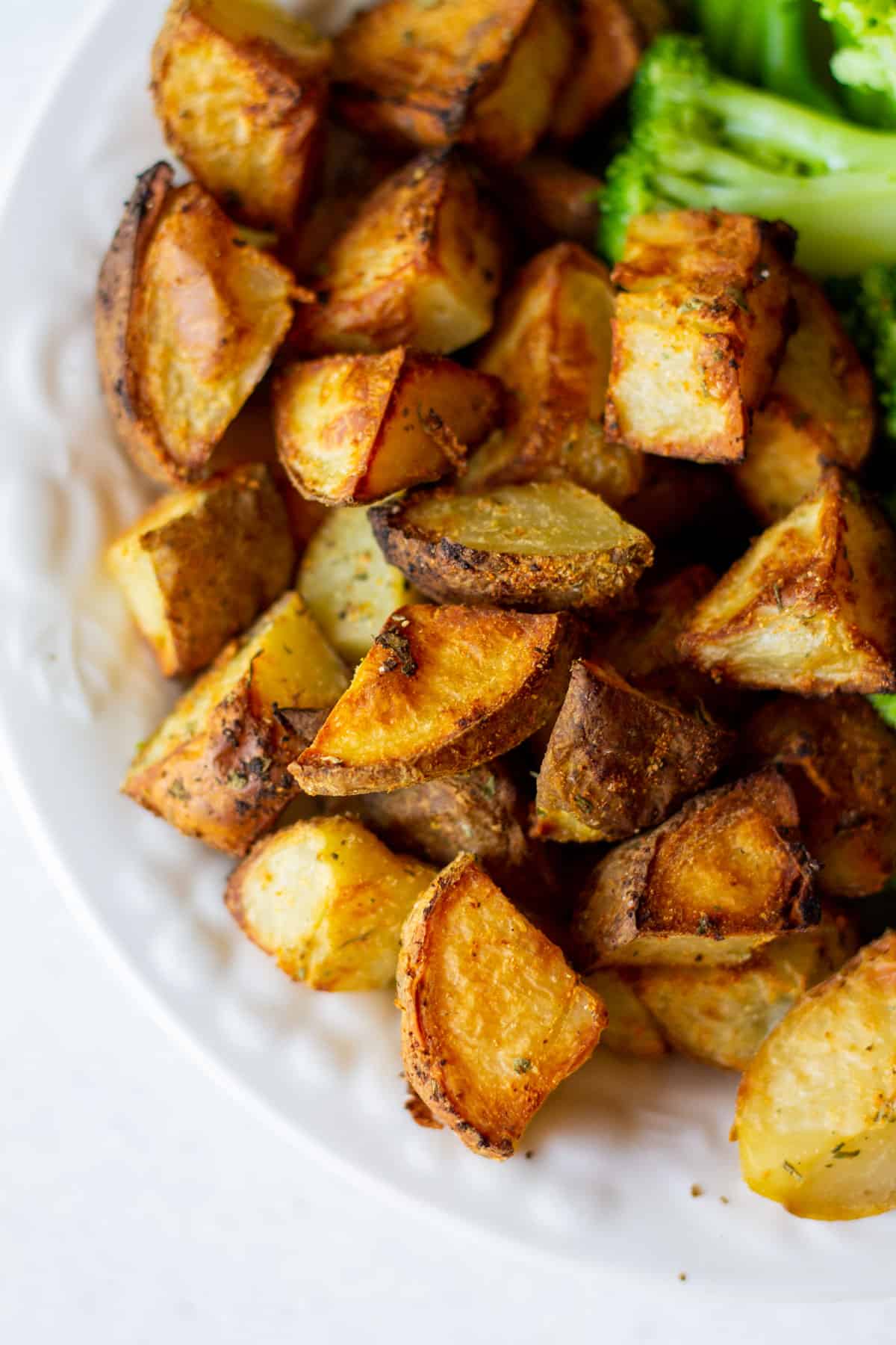 healthy roasted potatoes without oil in white bowl with steamed broccoli