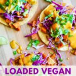 tostadas with beans, roasted sweet potato, red cabbage, avocado, vegan queso and cilantro on a wooden board with title "loaded vegan tostadas with roasted chili sweet potato"