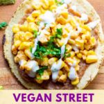 tostada with refried beans, dairy-free mexican street corn esquites, sour cream and cilantro on a wooden board with a lime in the background and title "vegan street corn tostadas"