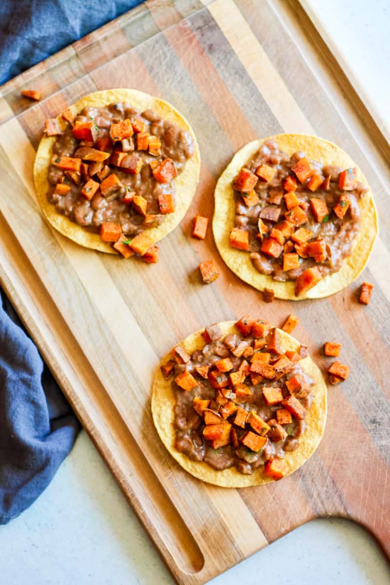 tostadas with beans, roasted sweet potato on a wooden board