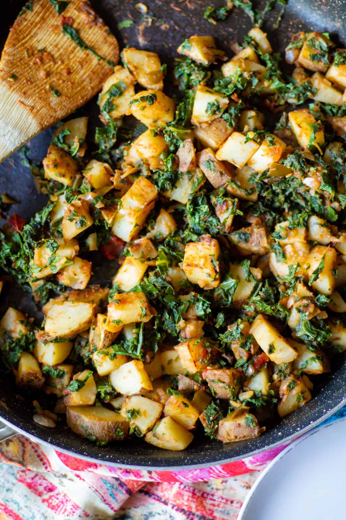 pan-seared skillet potatoes and wilted kale in non stick pan