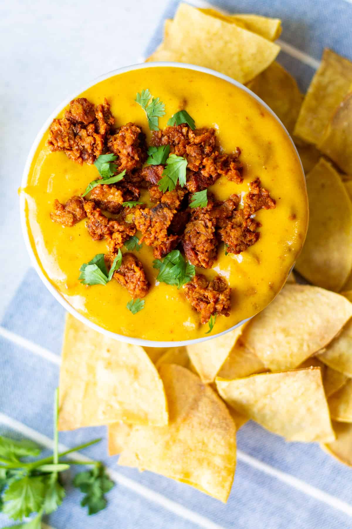 small bowl of vegan choriqueso with cilantro on top and chips on the side