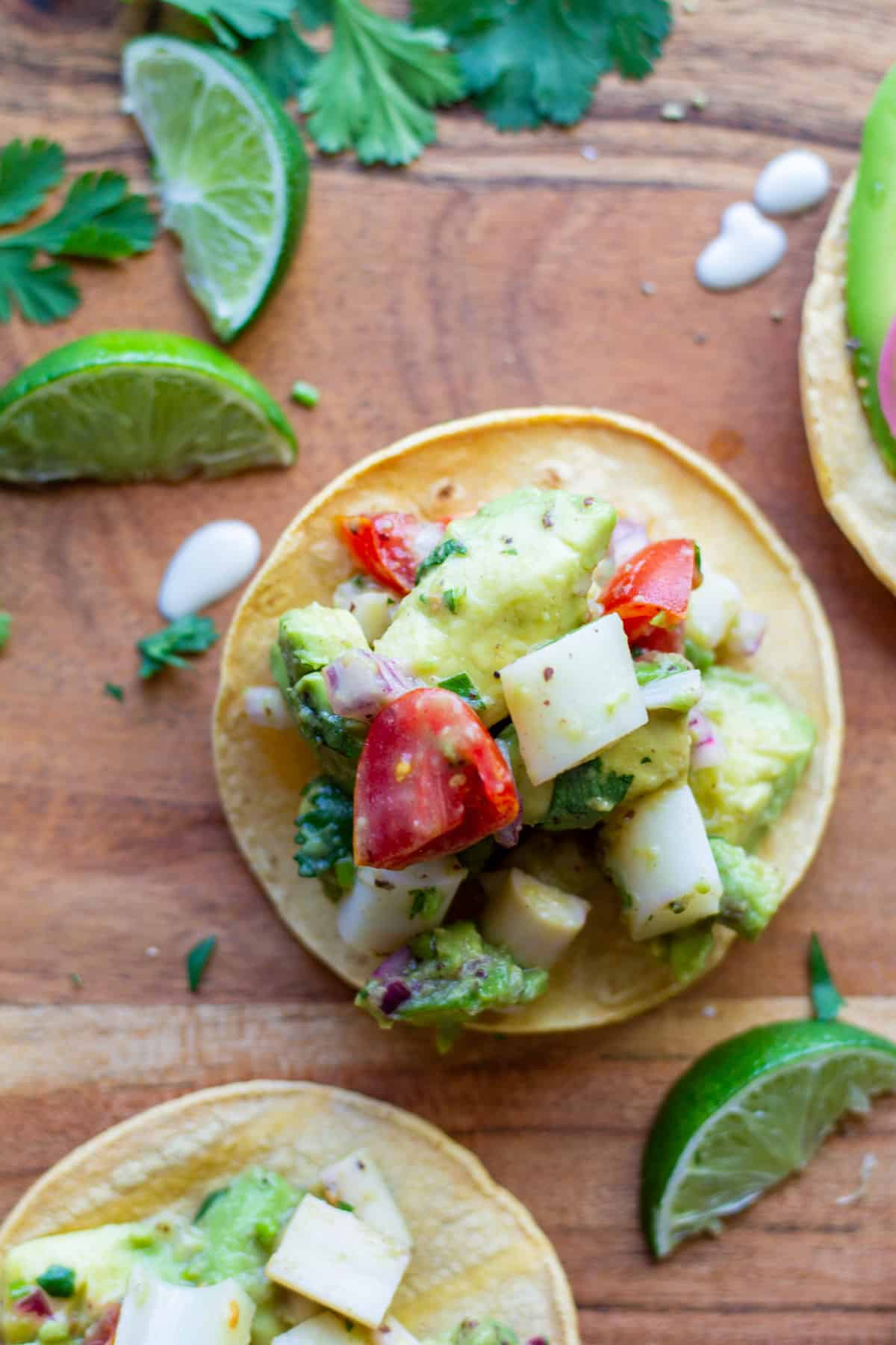 mini vegan ceviche tostada on wooden board with cut limes and cilantro on the side