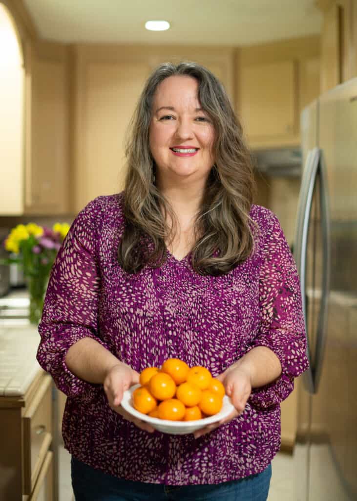 Abi holding a bowl of mandarin oranges in the kitchen