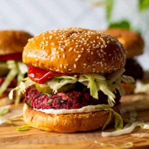 vegan beet burger with ketchup, mayo, lettuce, pickled and tomato on a sesame seed bun