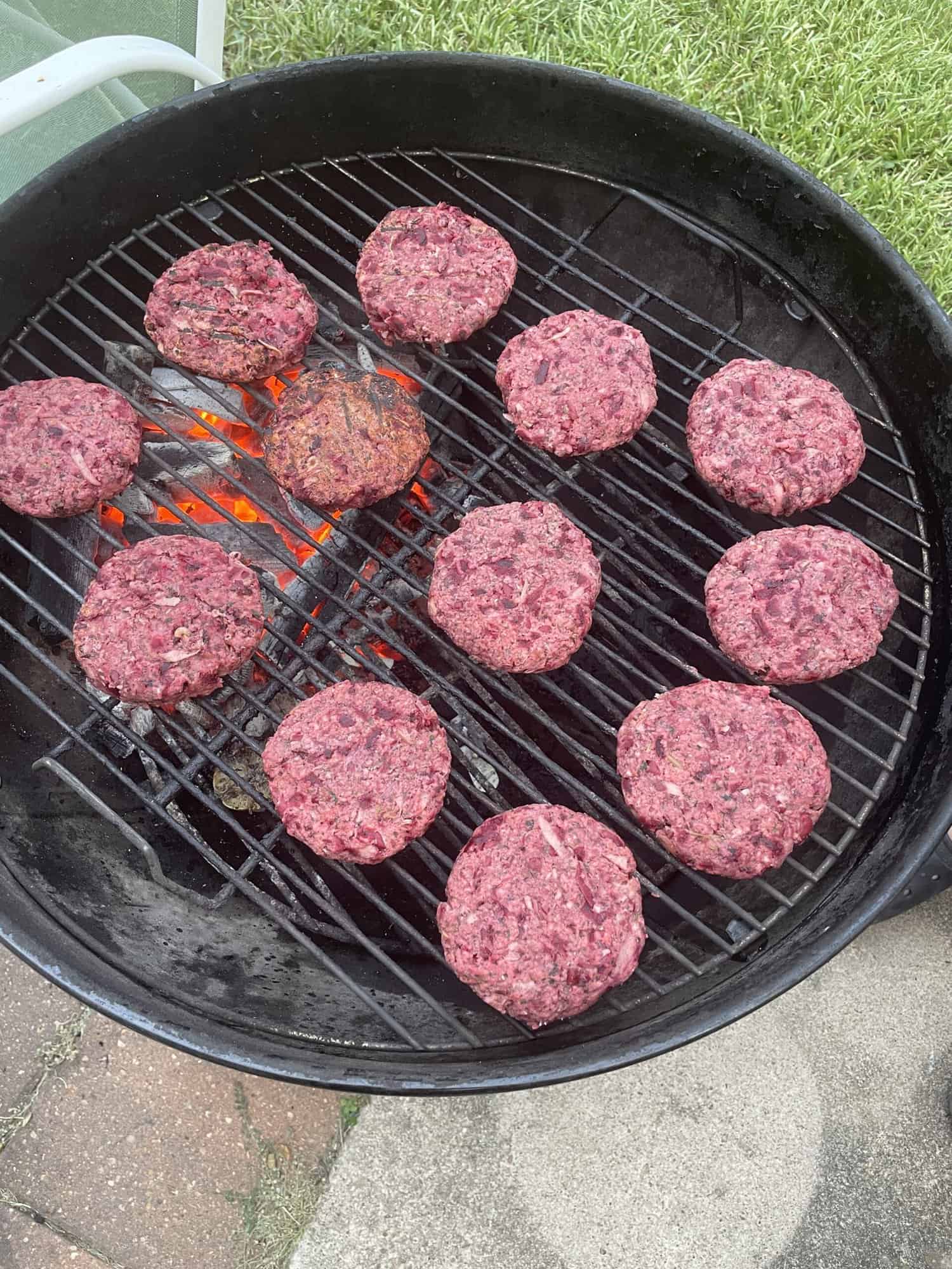 Grilling vegan beet burgers over charcoal Weber grill