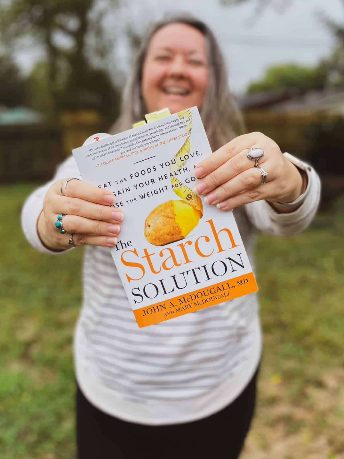 Abi Cowell of Very Veganish holding The Starch Solution book by John A. McDougall, MD and Mary McDougall