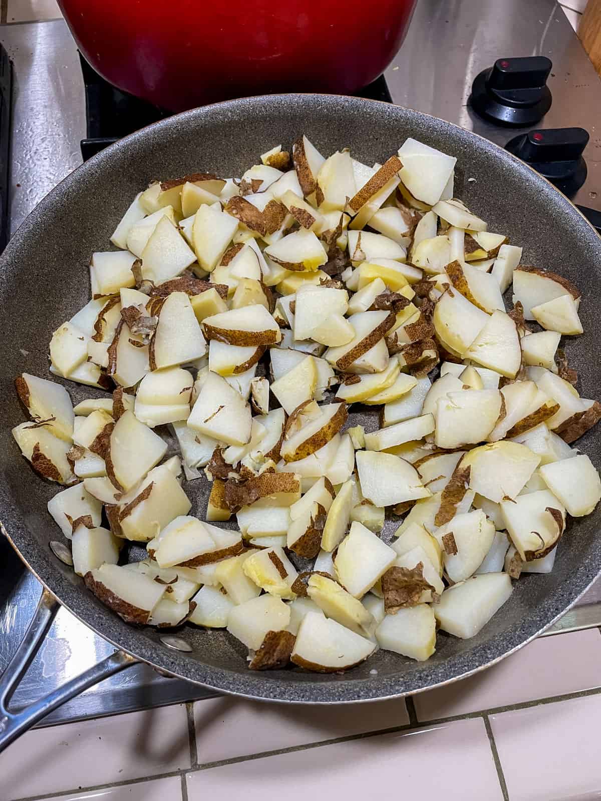 Heated non-stick pan with cut potatoes in it