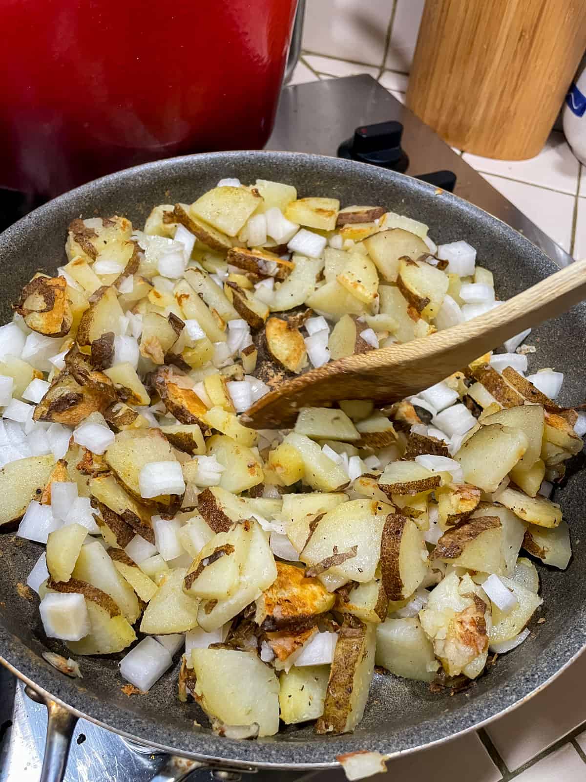 Stirring potatoes and onions in non-stick pan