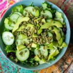 avocado cucumber salad with lettuce and pepitas in a blue bowl