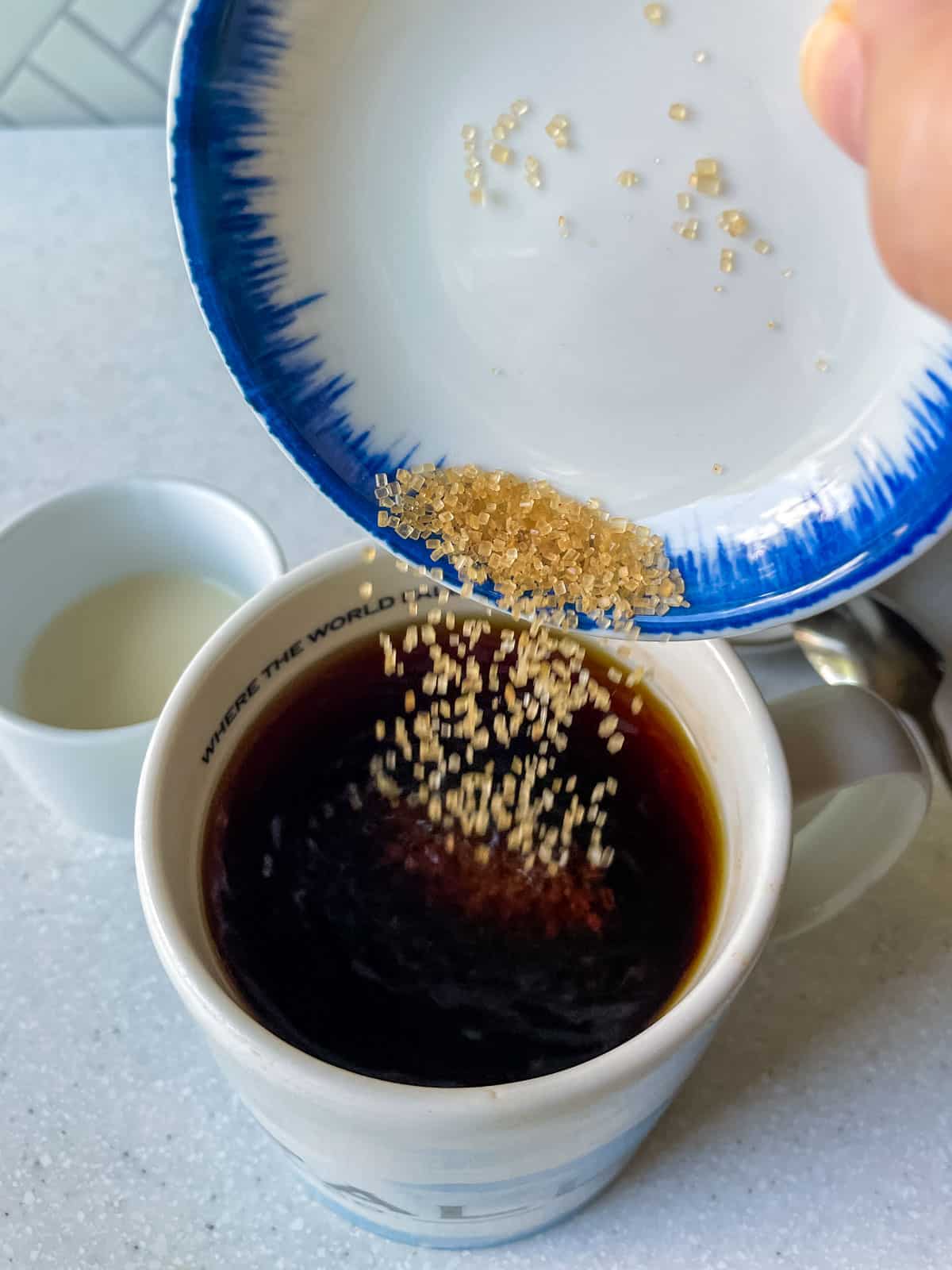 adding raw sugar to mug