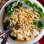 bowl of vegan noodle soup with greens, onion and tofu