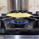 a yellow corn tortilla being reheated on the open flame of a gas stove burner