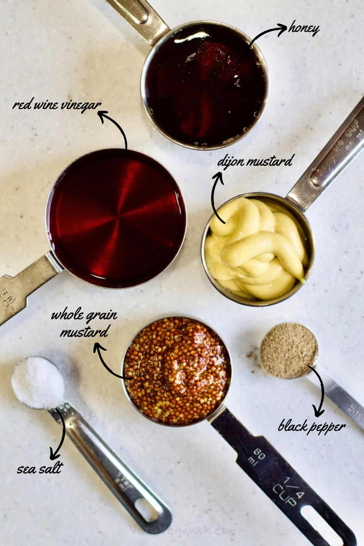 Ingredients for an oil-free honey mustard salad dressing measured out on counter: honey, dijon mustard, whole grain mustard, red wine vinegar, salt and black pepper