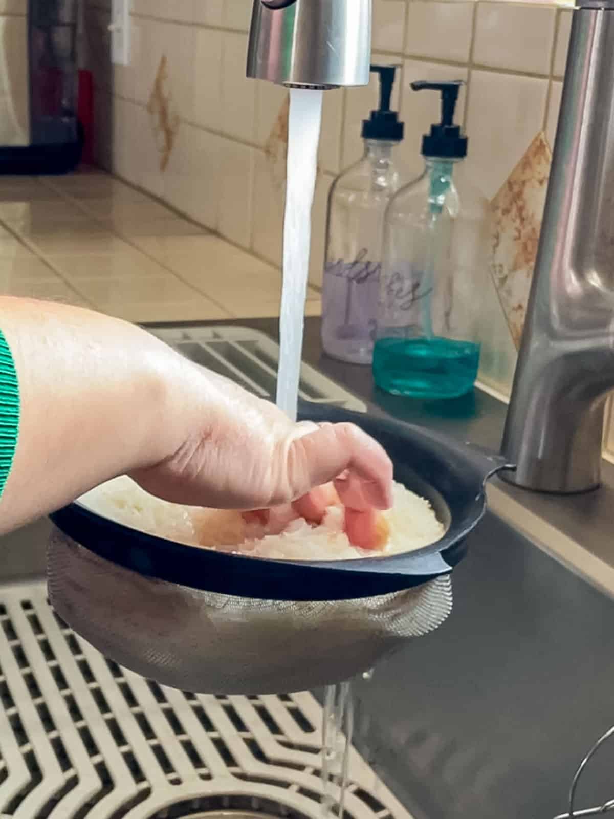 rinsing sushi rice in a large fine mesh sieve with cold water before cooking