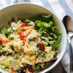 white bowl full of orzo pasta salad and spring mix