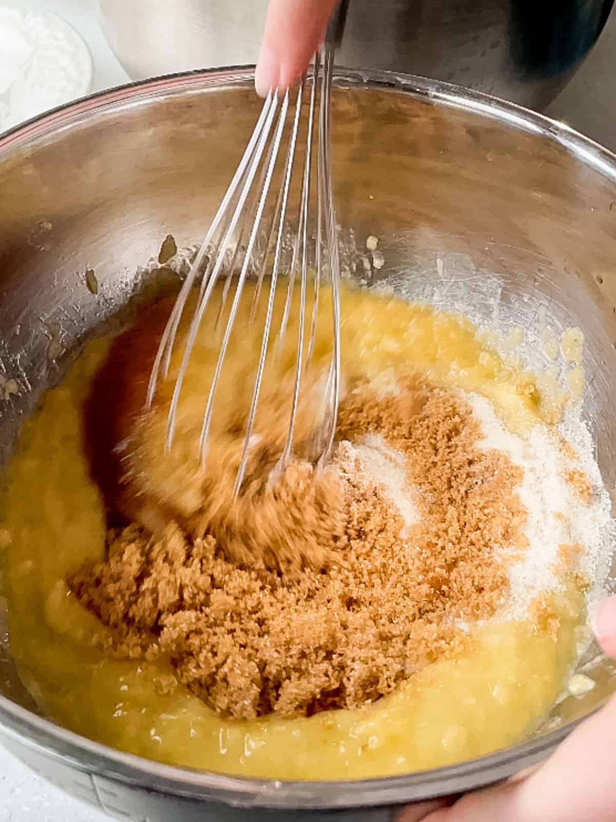 whisking wet ingredients together in stainless steel bowl