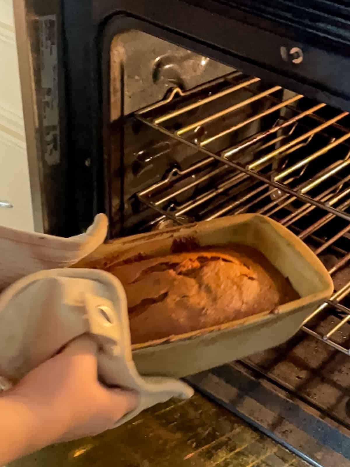 pulling baked banana bread out of oven