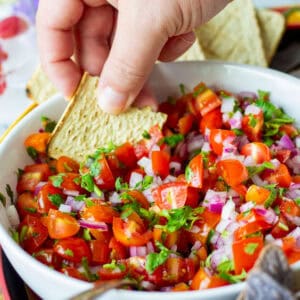 Dipping a chip into bowl of pico de gallo