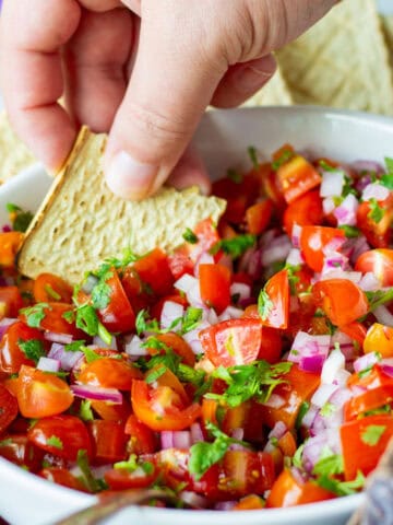 Dipping a chip into bowl of pico de gallo