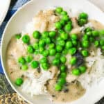 white bowl with steamed rice and almond milk mushroom gravy and green peas