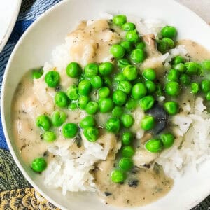 white bowl with steamed rice and almond milk mushroom gravy and green peas