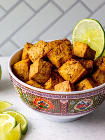 ginger lime tofu cubes in a bowl with lime wedges