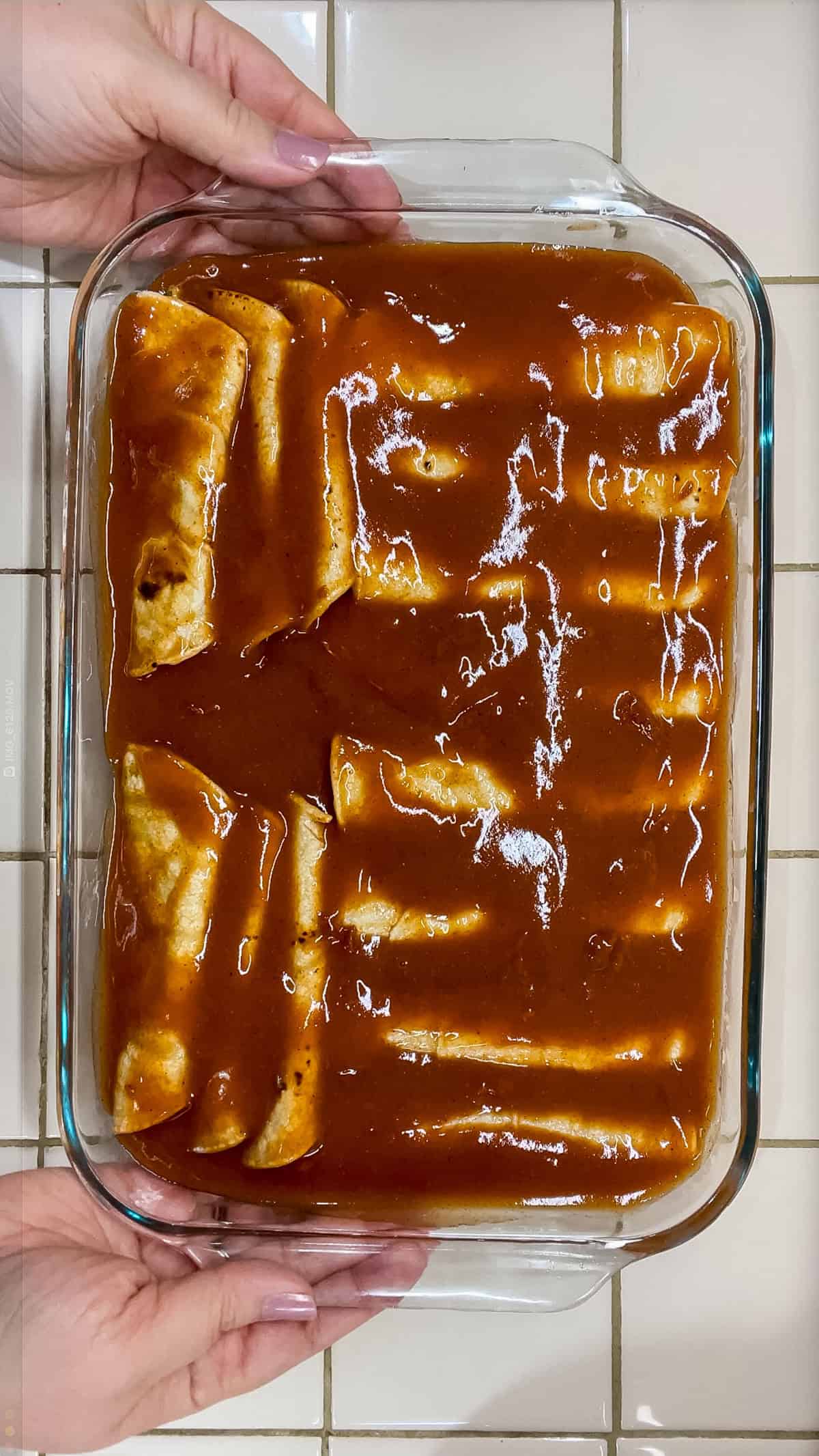Process Pour enchilada sauce on top and spread to cover all edges of tortillas