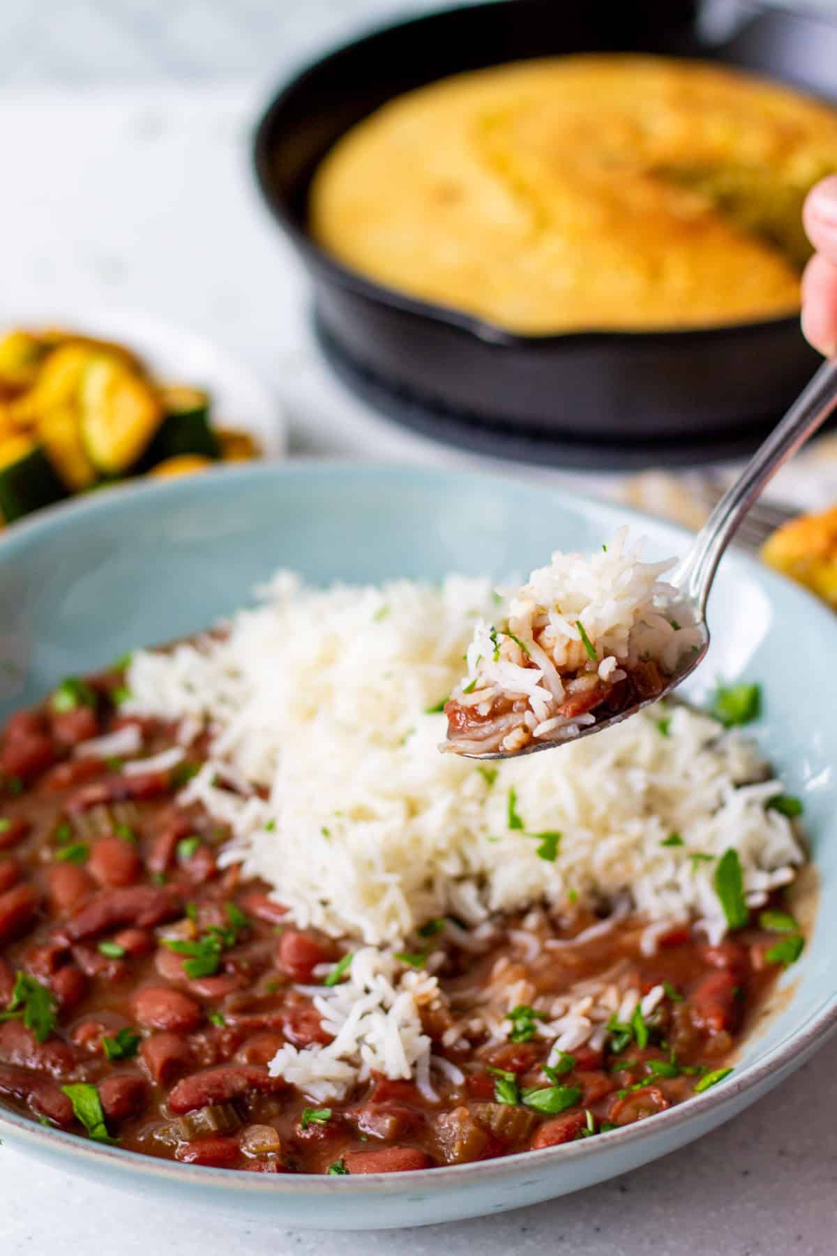 getting a spoonful out of a bowl of vegan red beans and rice with cornbread