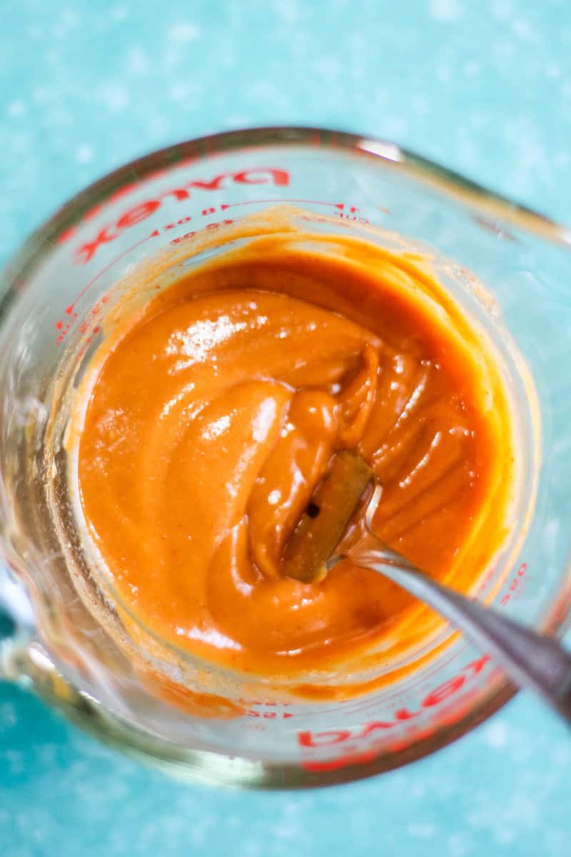 mixed peanut sauce in a glass measuring cup with fork