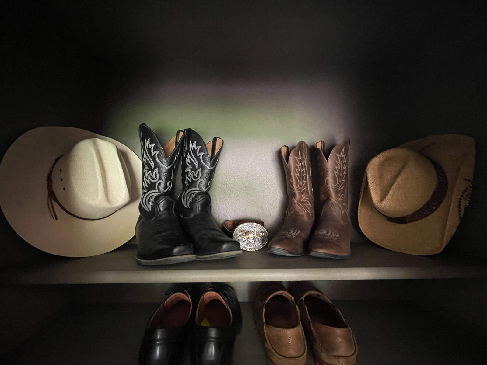 Finished shot of shoe closet filled with shoes with cowboy boots and hats on top shelf