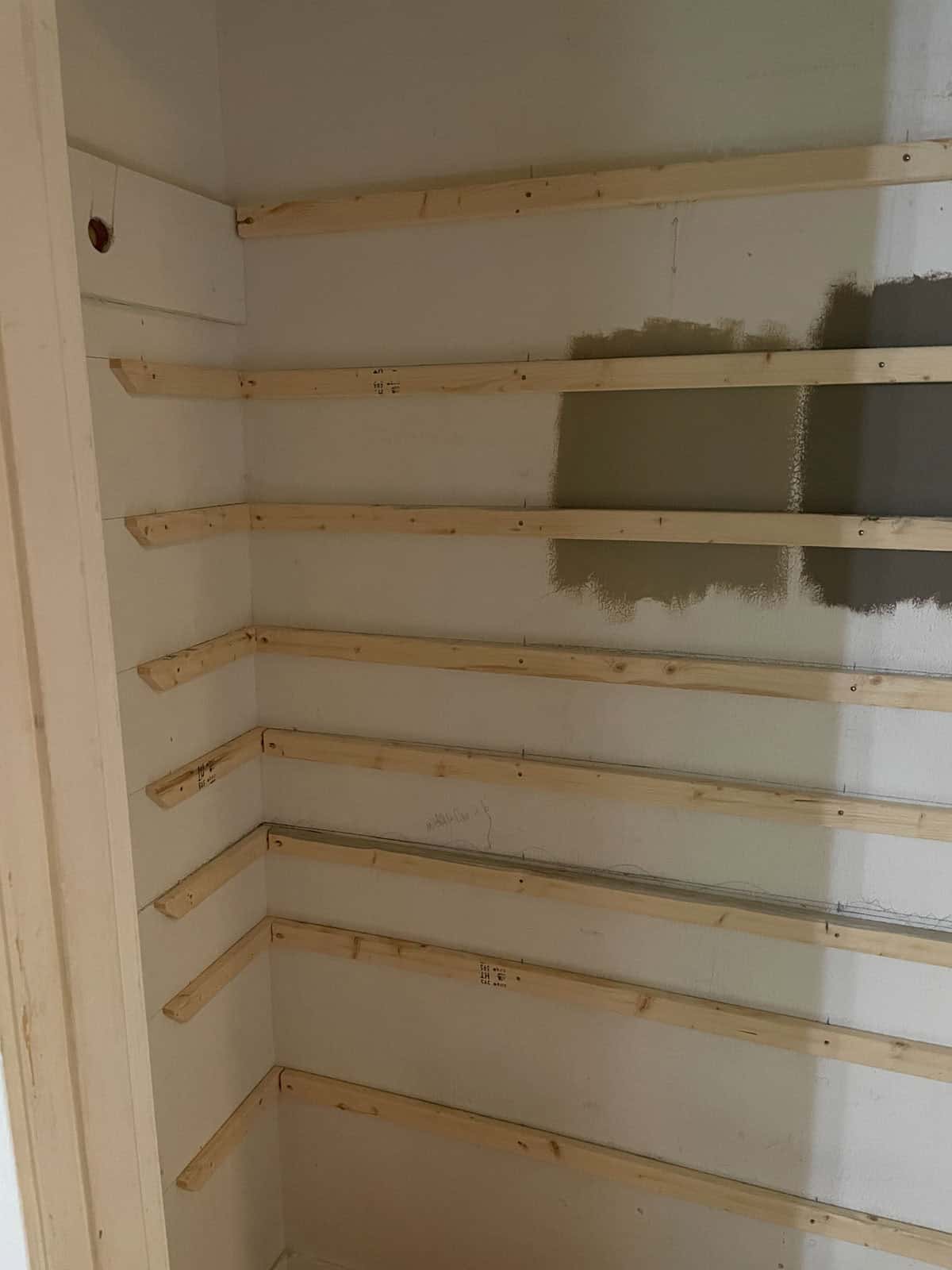 Process photo of DIY shoe closet, with support boards screwed to wall, before painting.