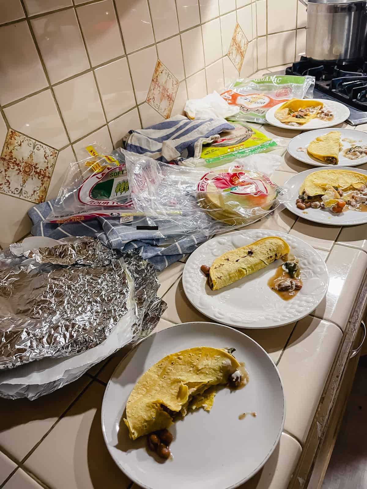 counter full of corn tortillas reheated various ways filled with beans and sour cream to see which one is strongest and best tasting