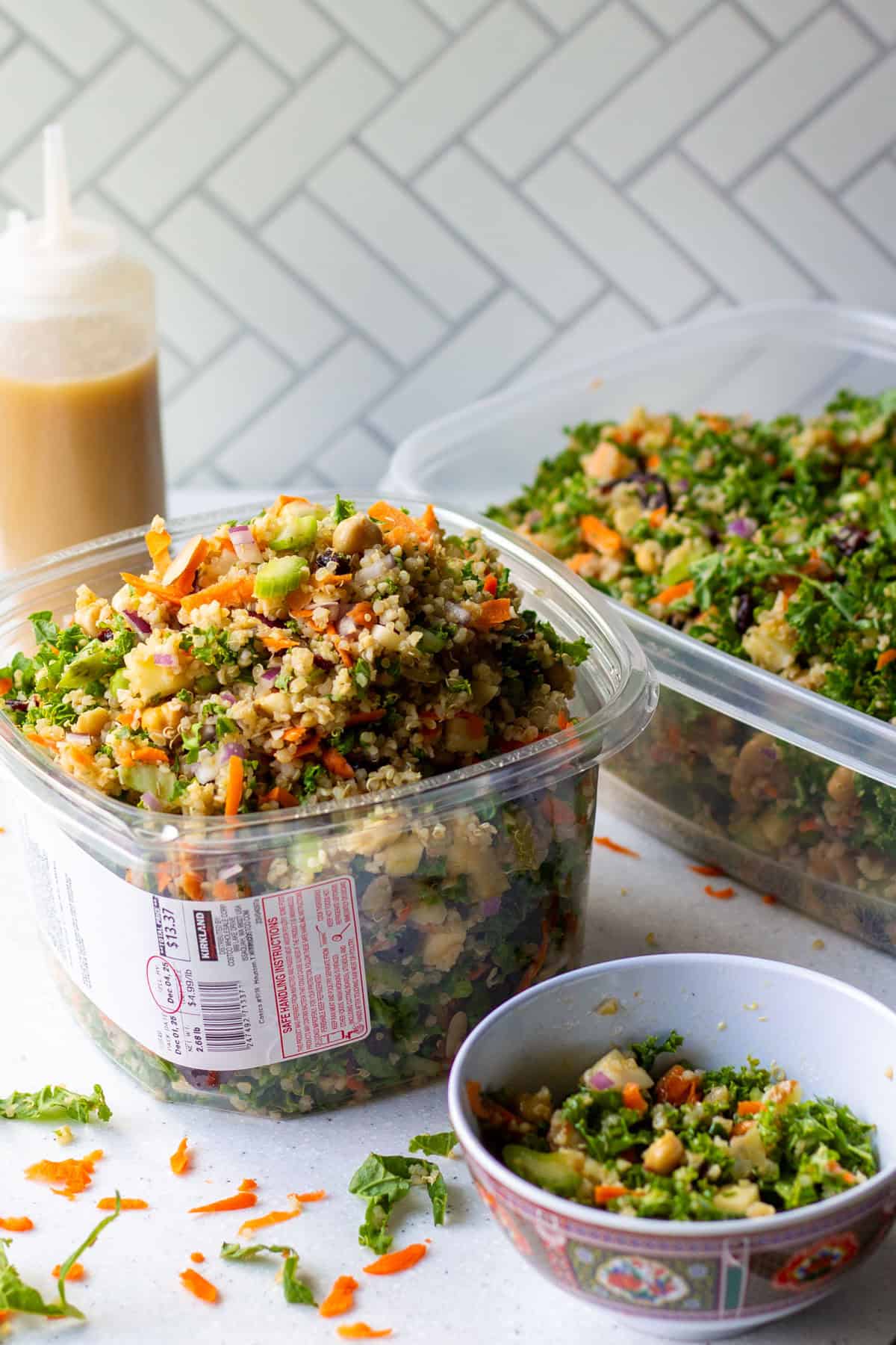 Packed over the top grain and celery copycat Costco salad recipe in a Kirkland plastic container with homemade apple cider vinaigrette dressing in background