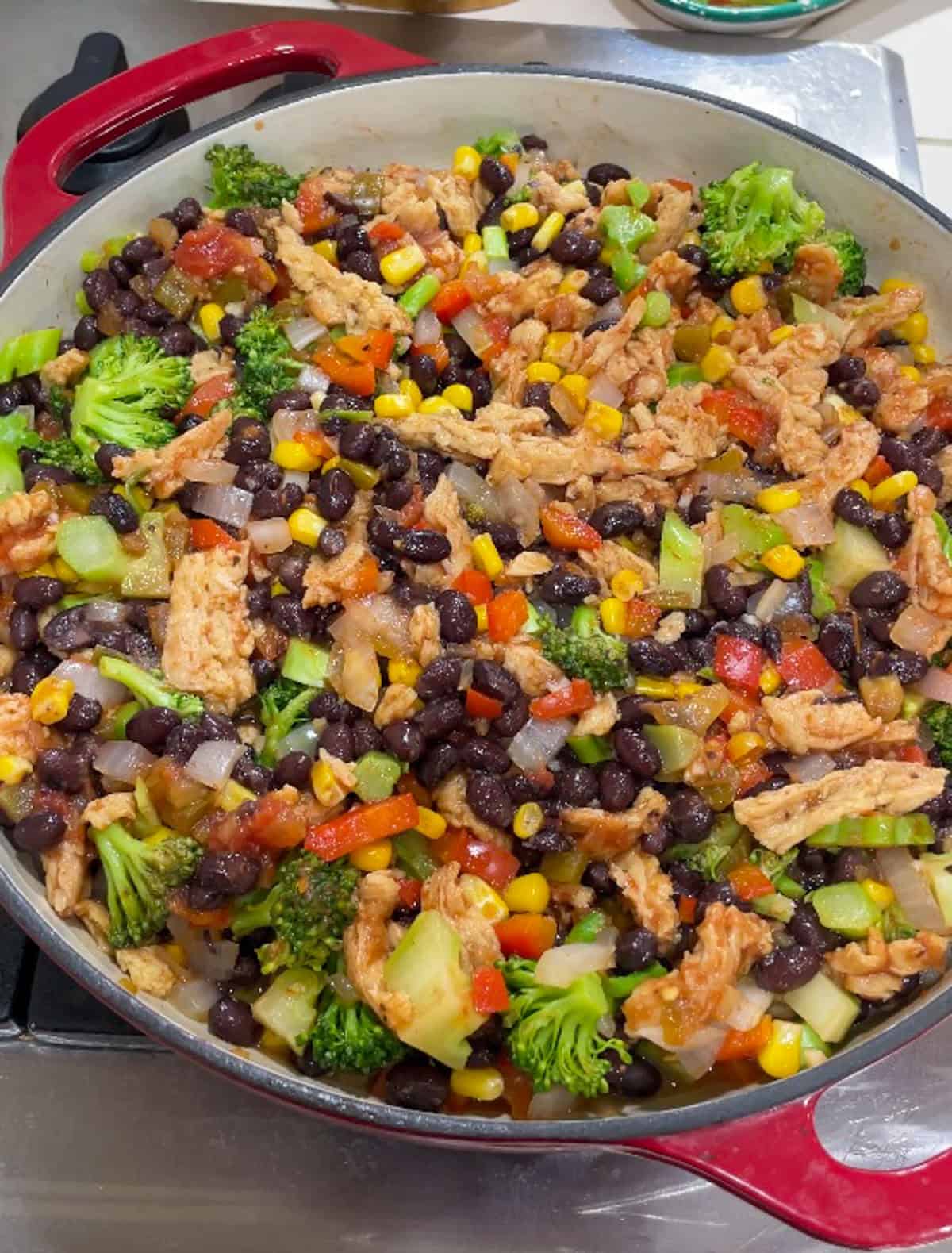 Process shot of adding soy curls, corn, black beans and salsa and then letting mixture simmer