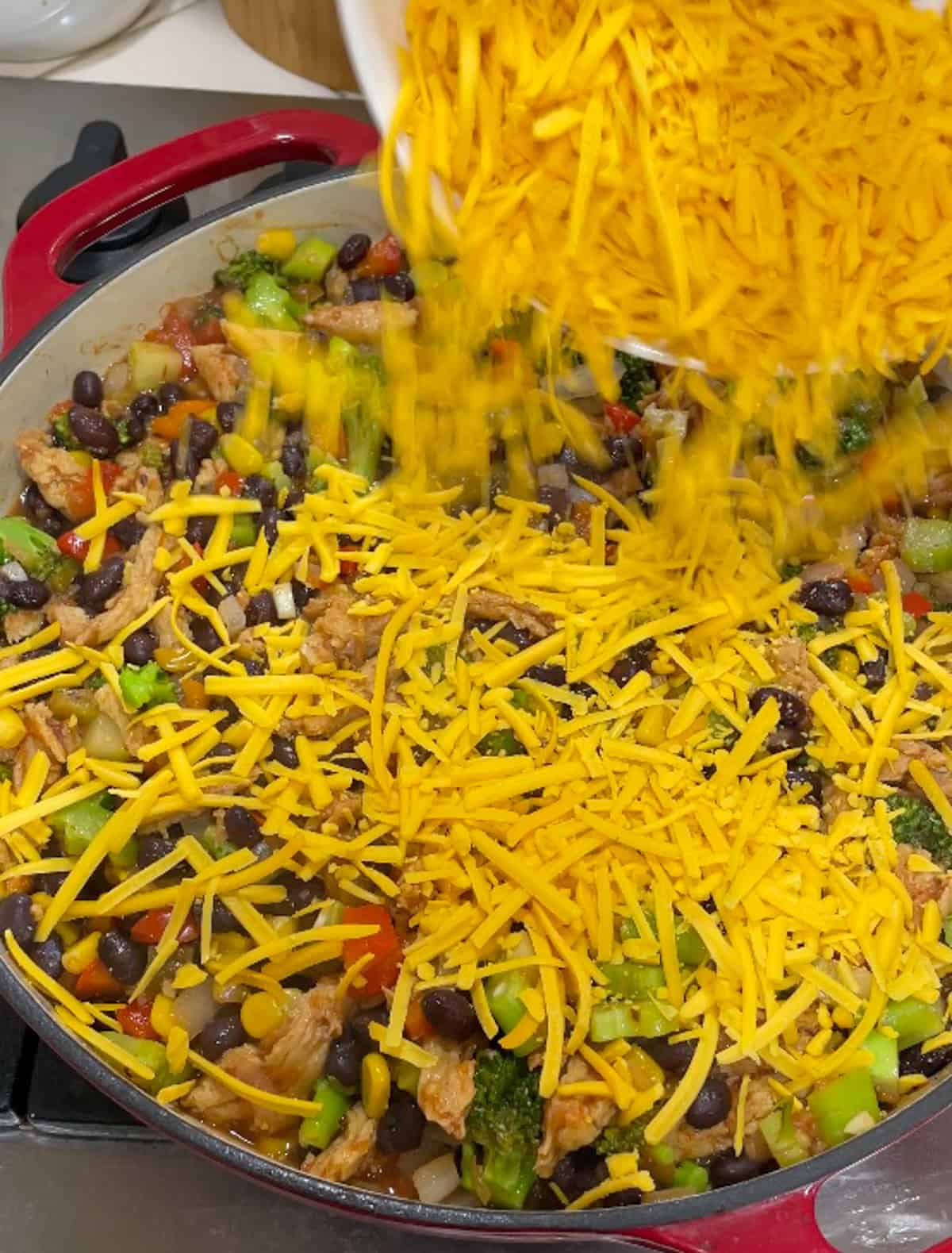 sprinkling non-dairy shredded cheese over taco mixture in the skillet on the stove