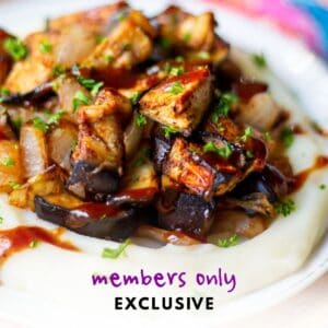 plate with roasted BBQ eggplant and onion on a bed of mashed potatoes with BBQ sauce drizzled on top - label reads "members only exclusive"