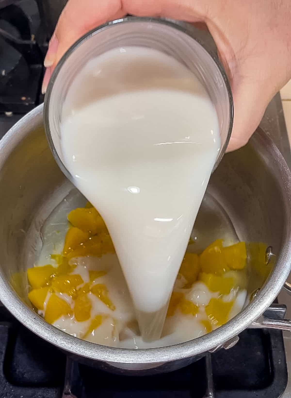 pouring almond milk into pan with peach preserves and canned peaches