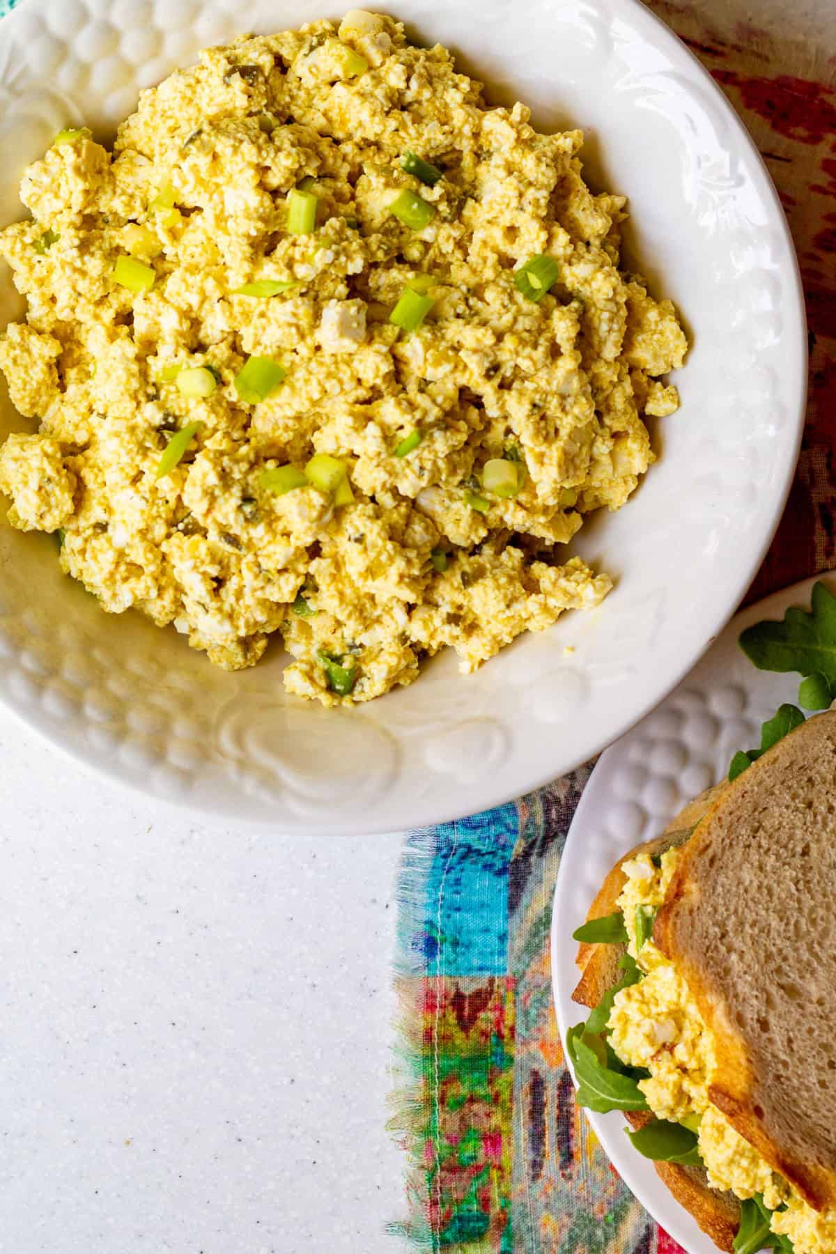 big white bowl of tofu egg salad, with sandwich nearby