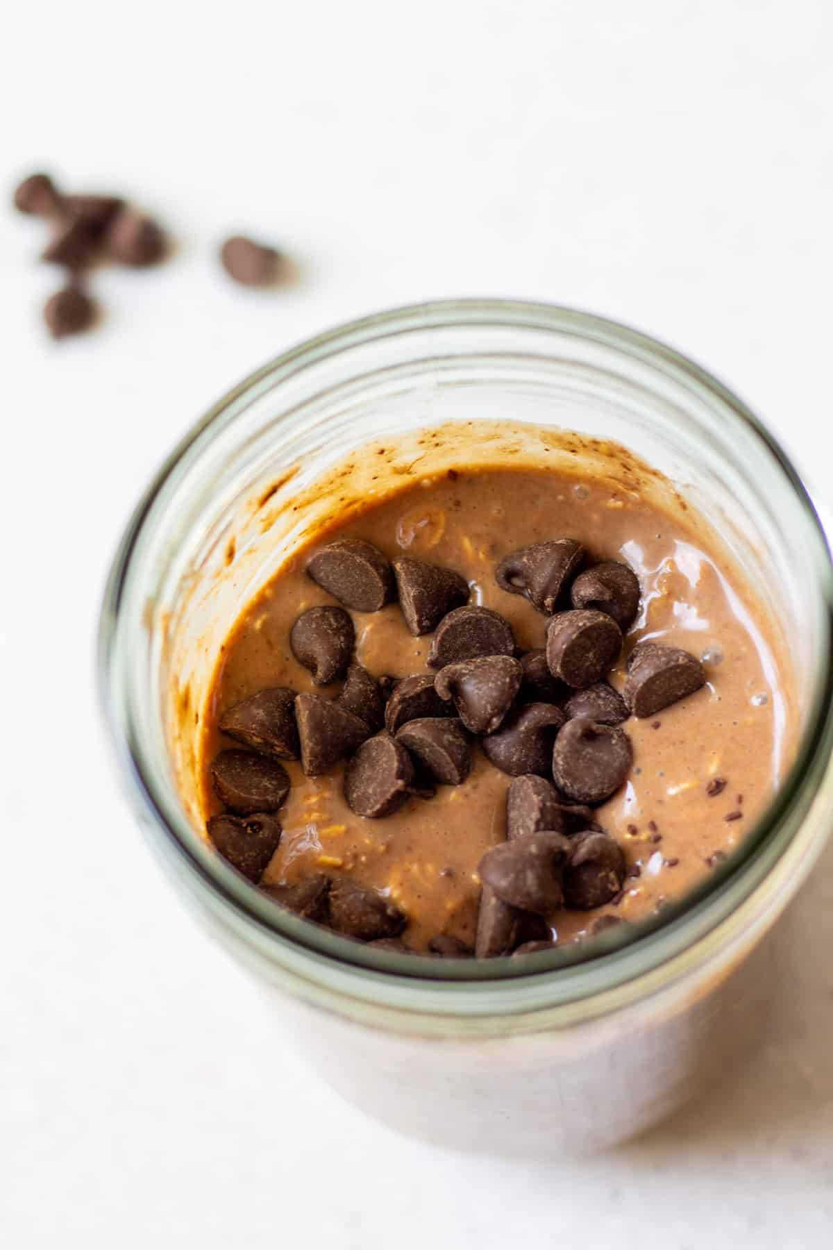 Overhead view of double chocolate overnight oats in a jar with vegan chocolate chips on top.