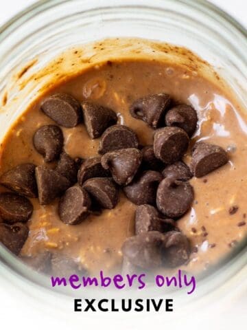 Close-up of vegan double chocolate overnight oats in a glass jar topped with dairy-free chocolate chips.