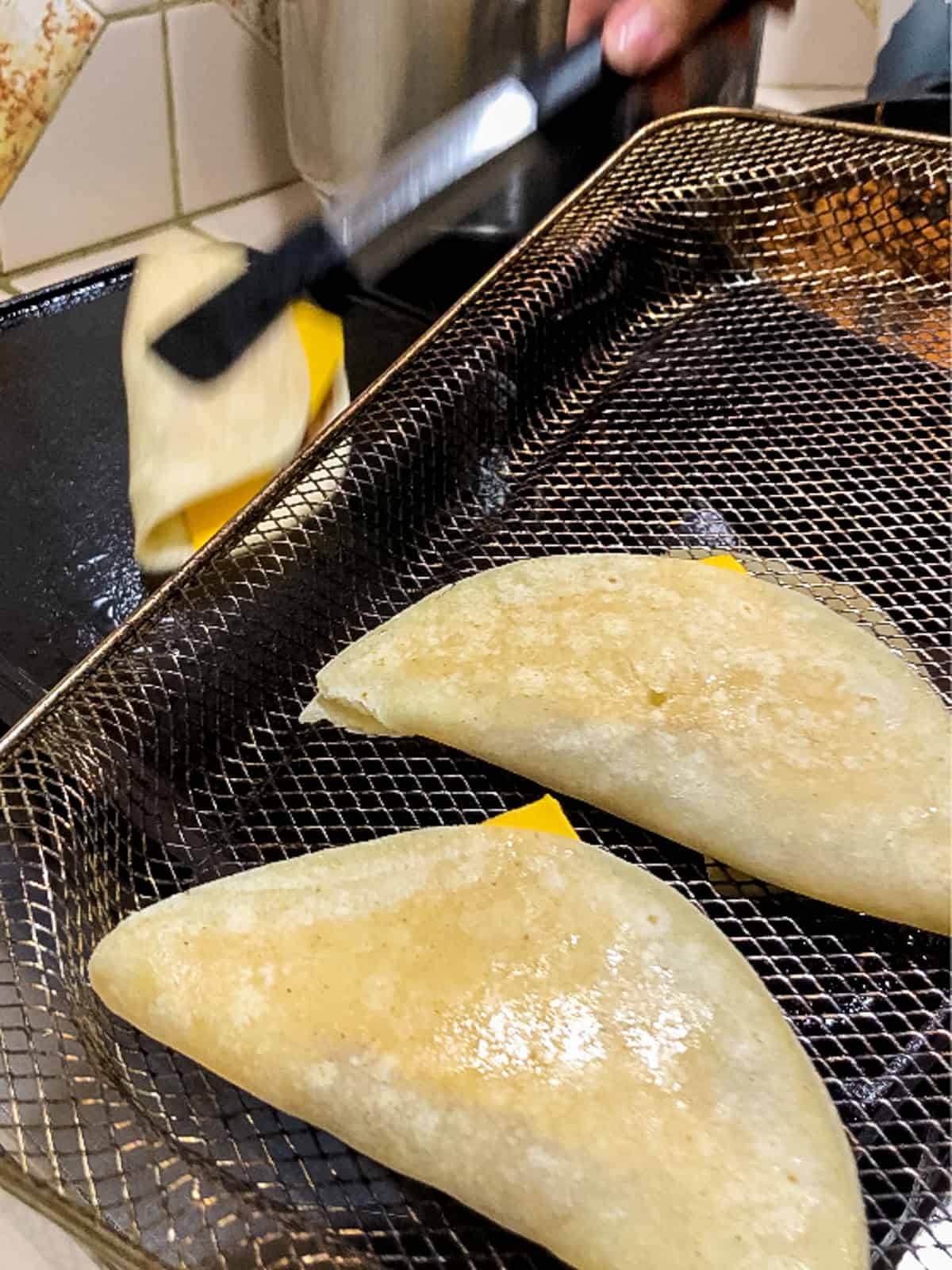Cooked vegan tacos in air fryer basket, ready to crisp for Jack in the Box copycat recipe.
