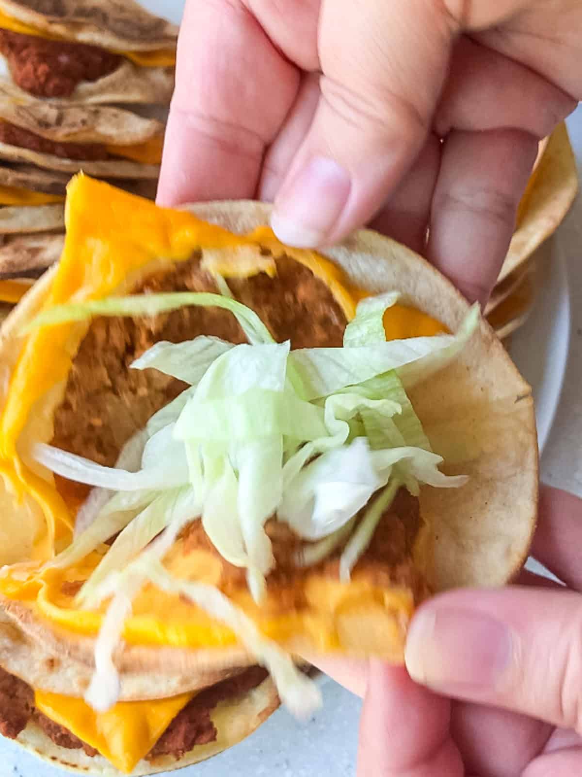 Vegan Jack in the Box style taco topped with shredded lettuce, ready to eat.