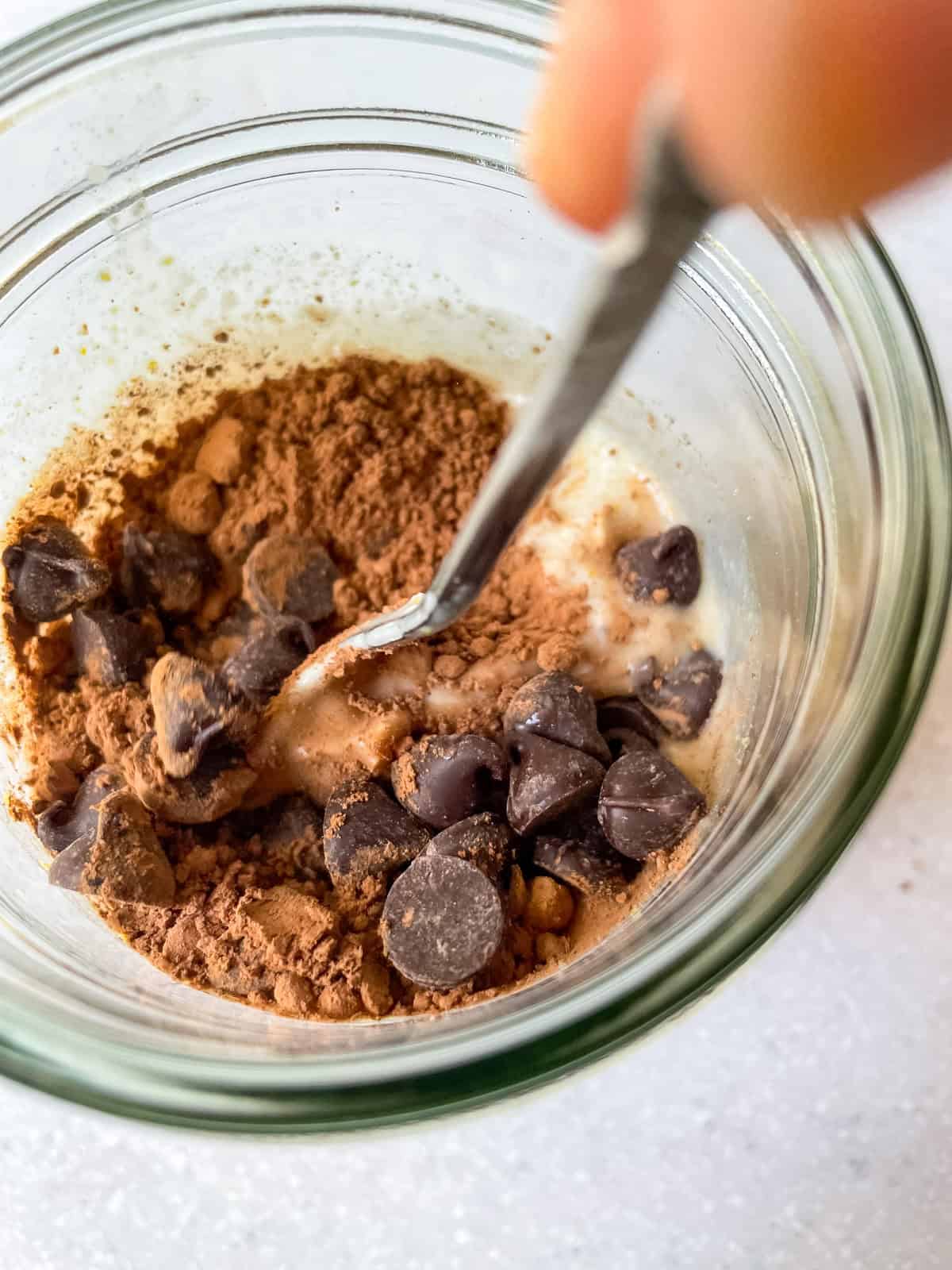 Stirring cocoa powder, vegan chocolate chips, and oats in a jar to make double chocolate overnight oats.