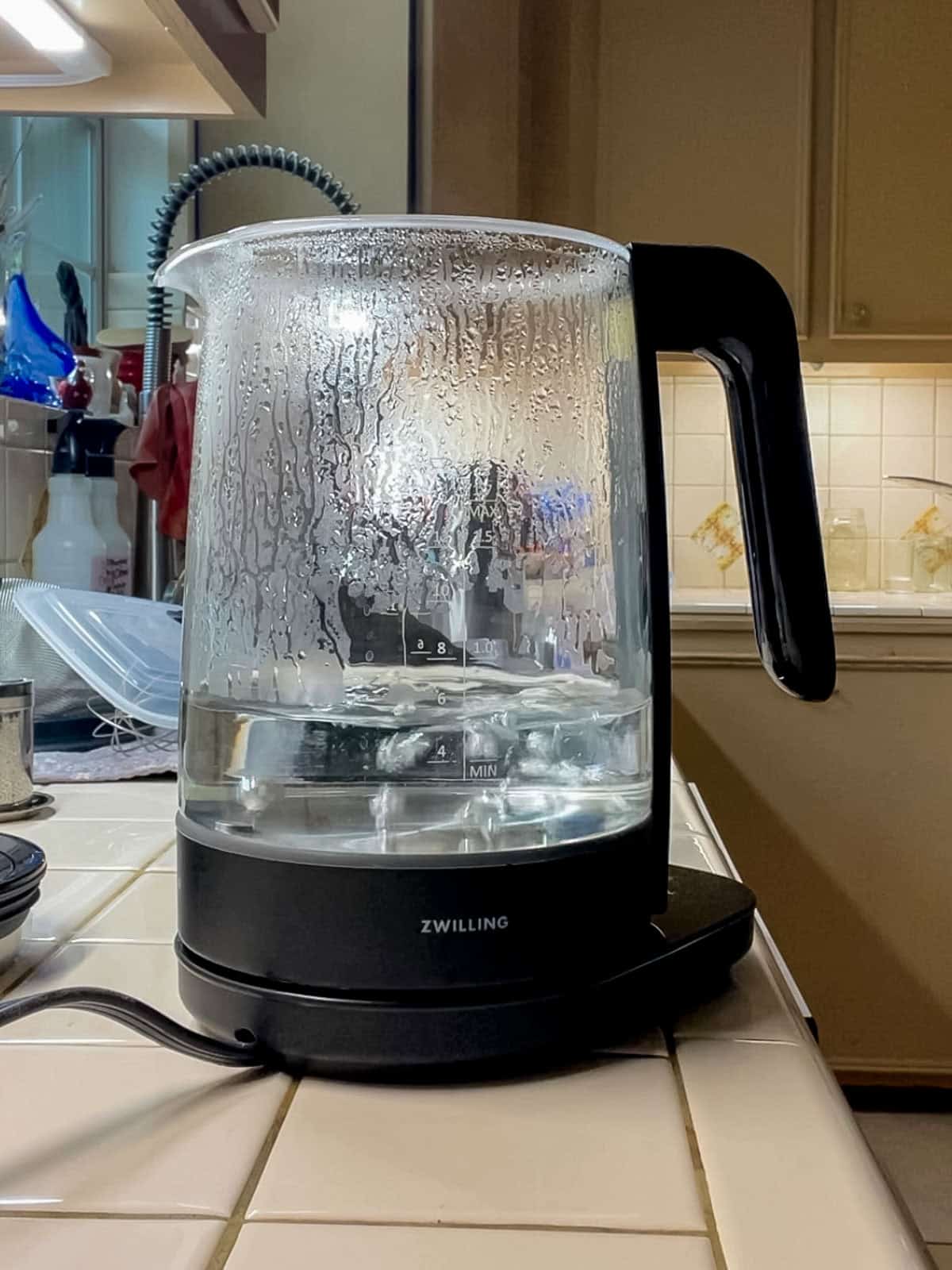 Boiling a vinegar and water solution in an electric kettle to dissolve hard water deposits and clean limescale naturally.