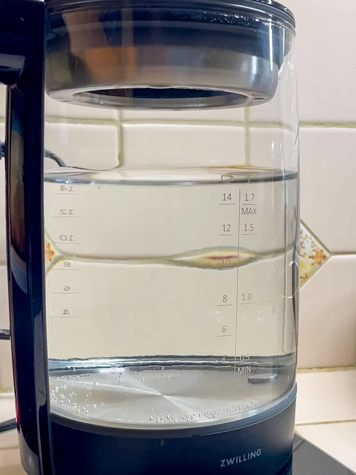 Clean electric kettle after removing limescale with white vinegar, showing clear water and a spotless interior.